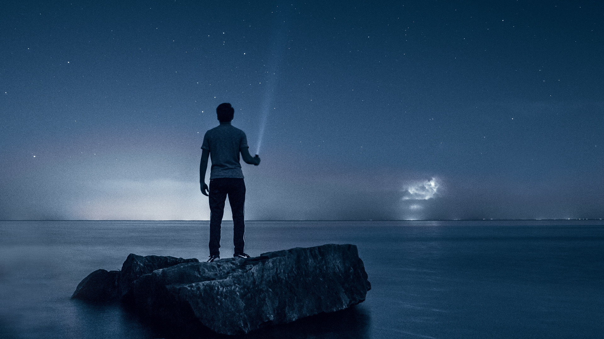 Man Standing on rock holding a flashlight