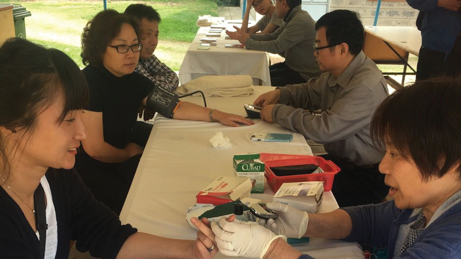 People sitting along a table receiving medical aid