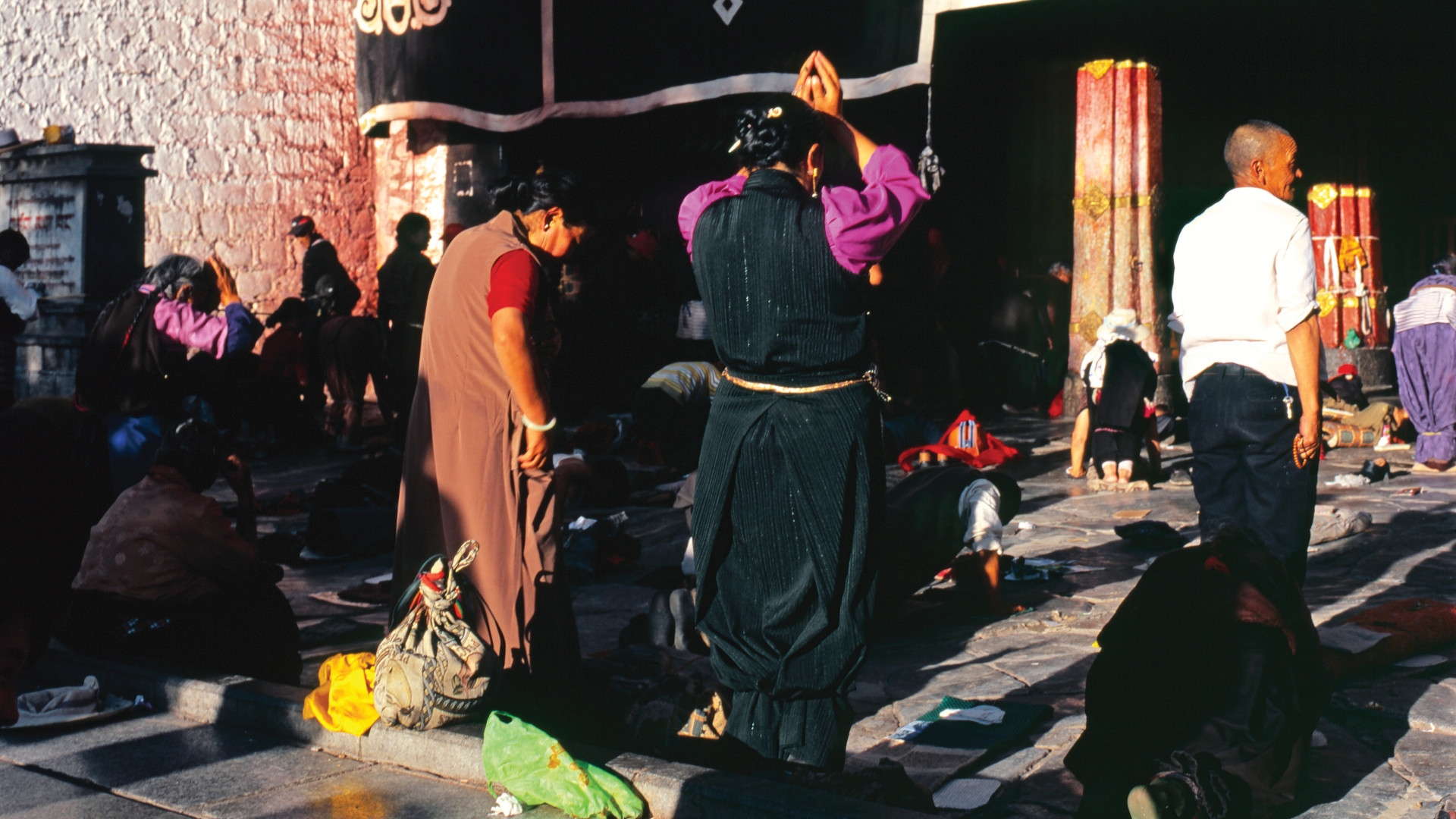 Two women praying amongst other worshipers